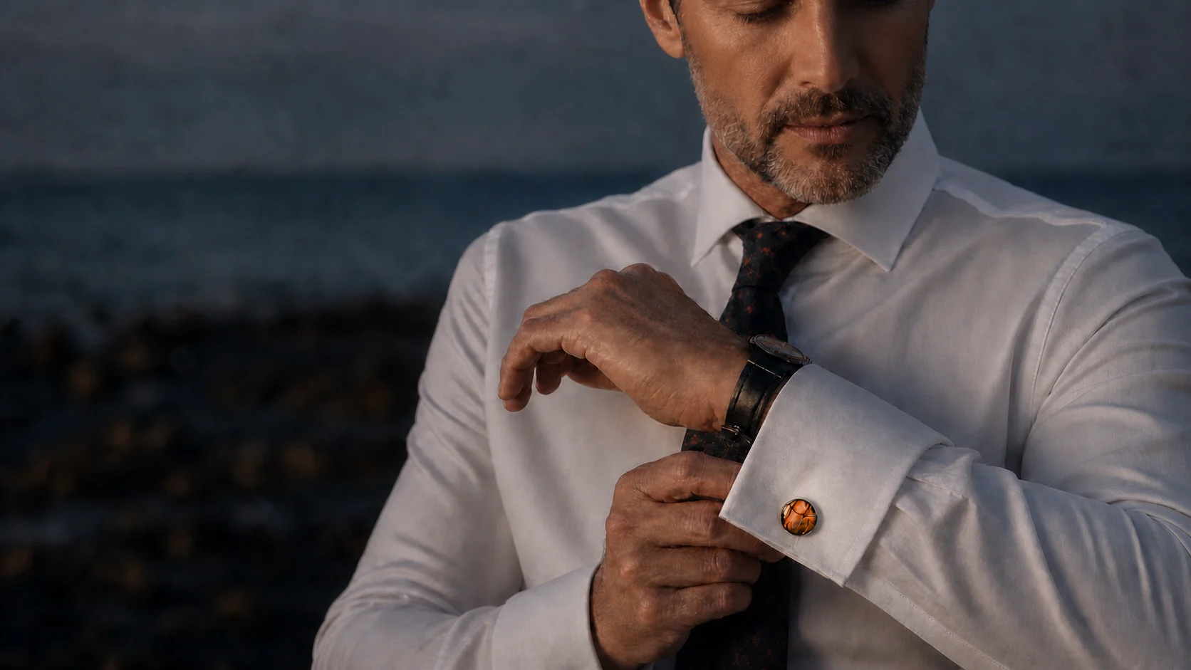 Man in evening wear adjusting his watch and wearing a Wild Shore amber fluid-art cufflink