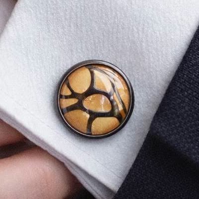 The actual cufflink — amber-gold cells over black in glass