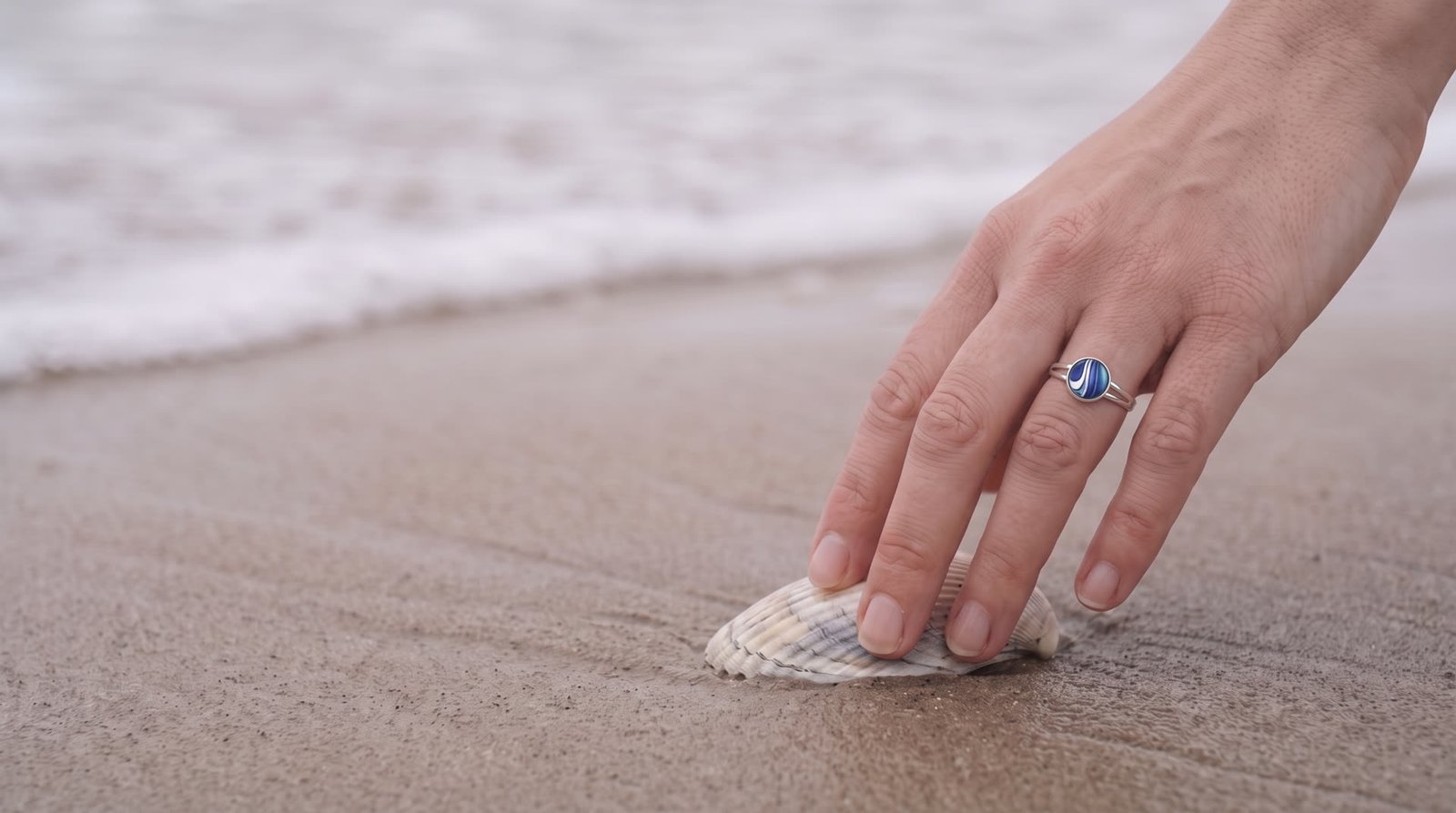 Hand on the shore wearing a Wild Shore blue fluid art ring